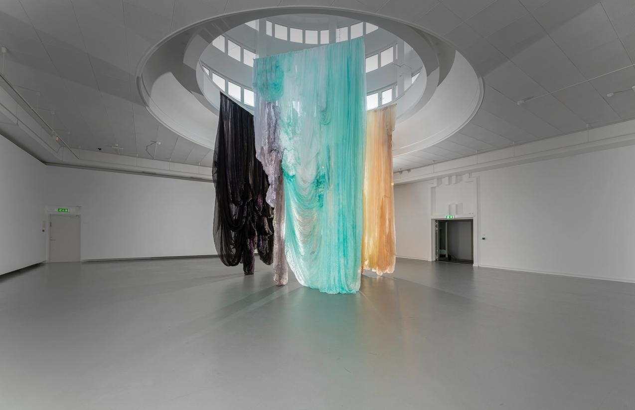 Overview of monumental textile installation hanging from ceiling.